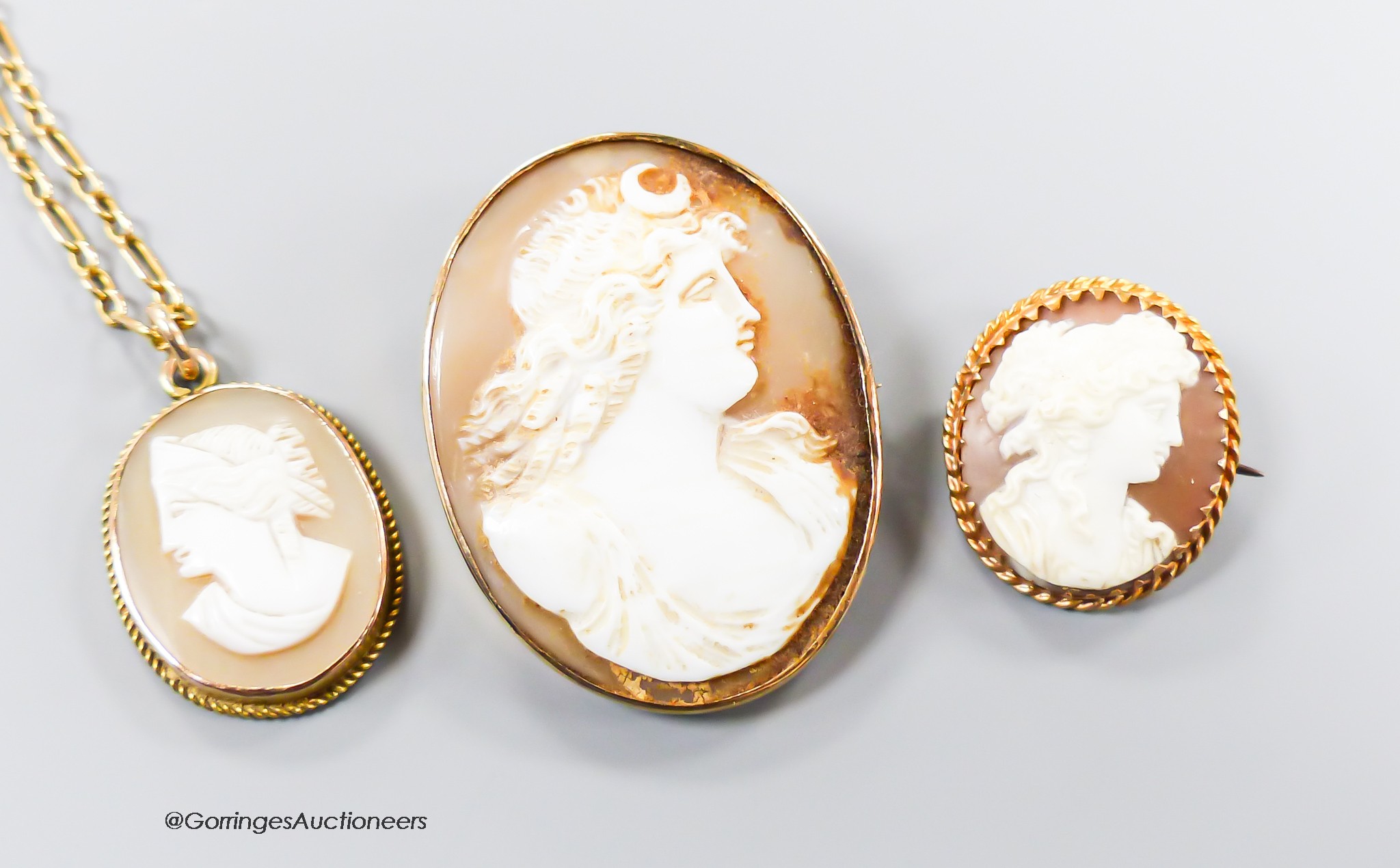 A 9ct gold mounted cameo shell pendant, 21mm, on a 9kt chain, gross 6.1 grams and two cameo shell brooches